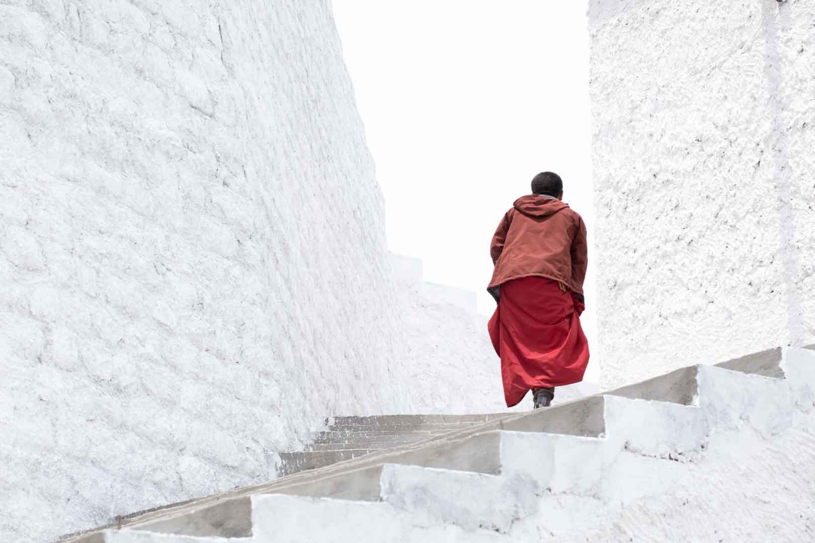 Person in red walking up white steps