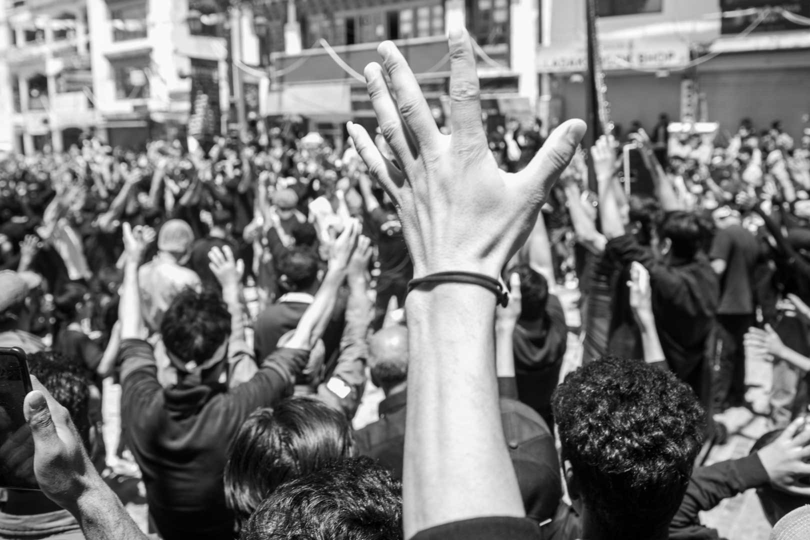 Raised hand above a crowd in black and white