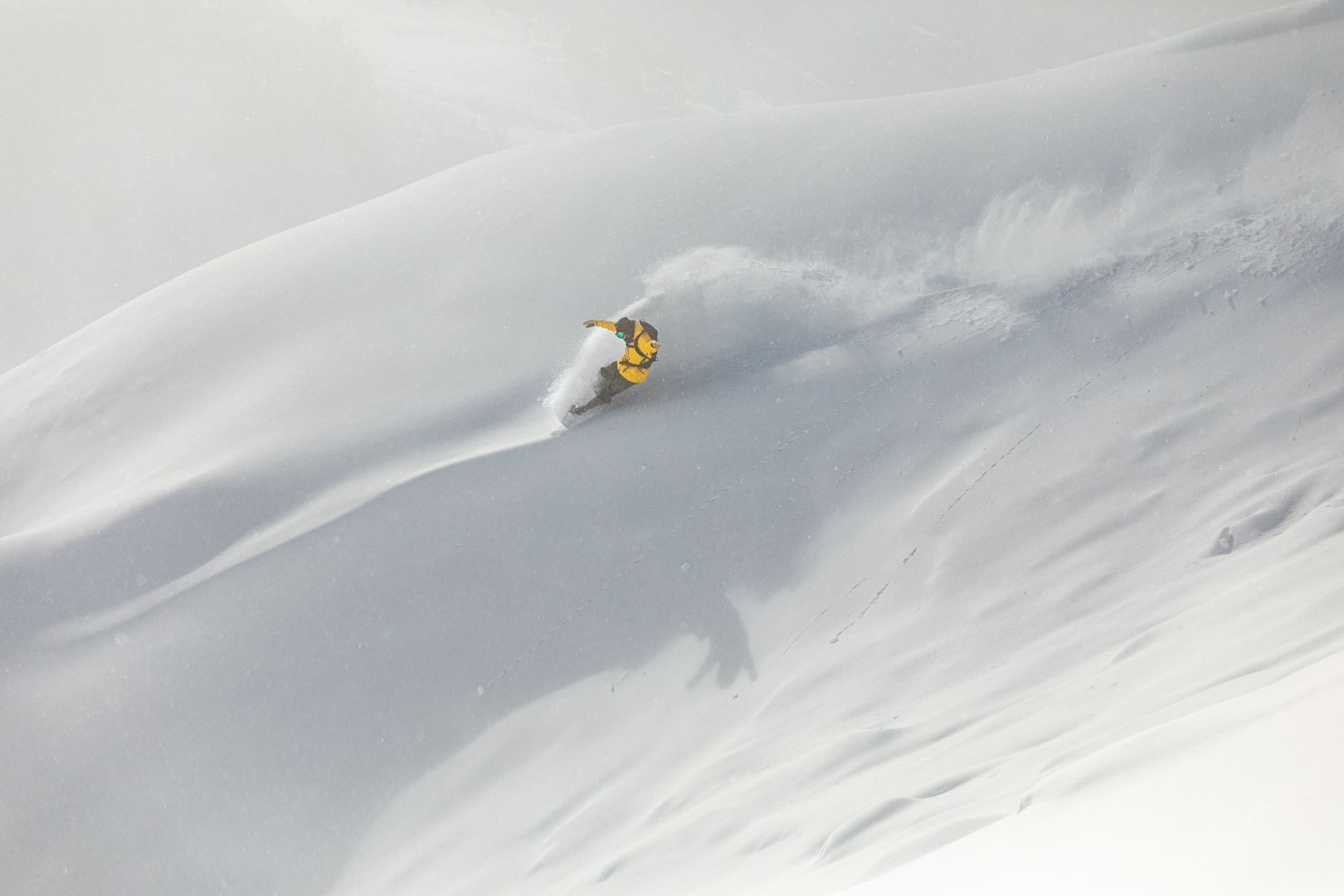 Snowboarder carving through deep powder
