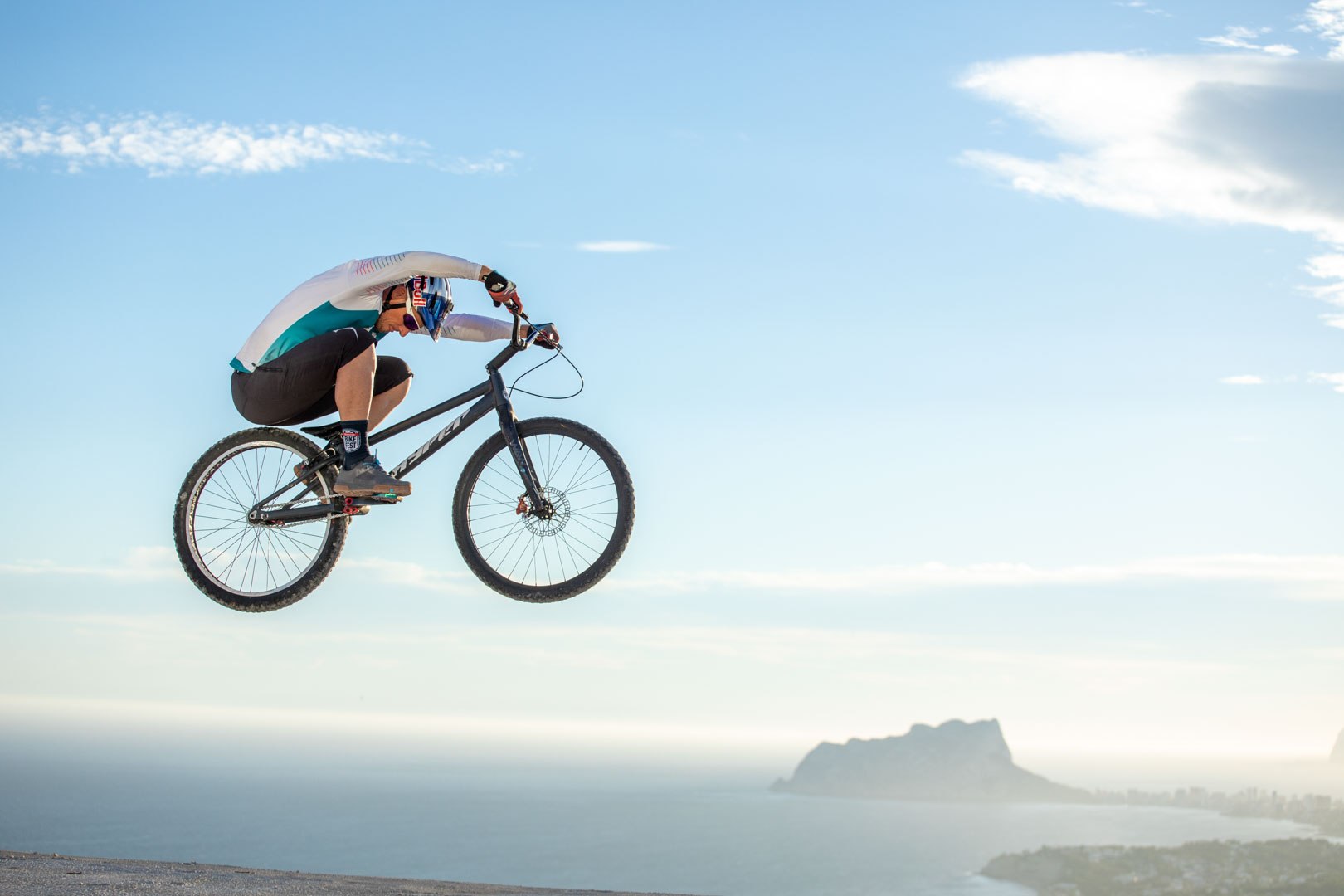 Bike trials rider suspended above a coastal landscape