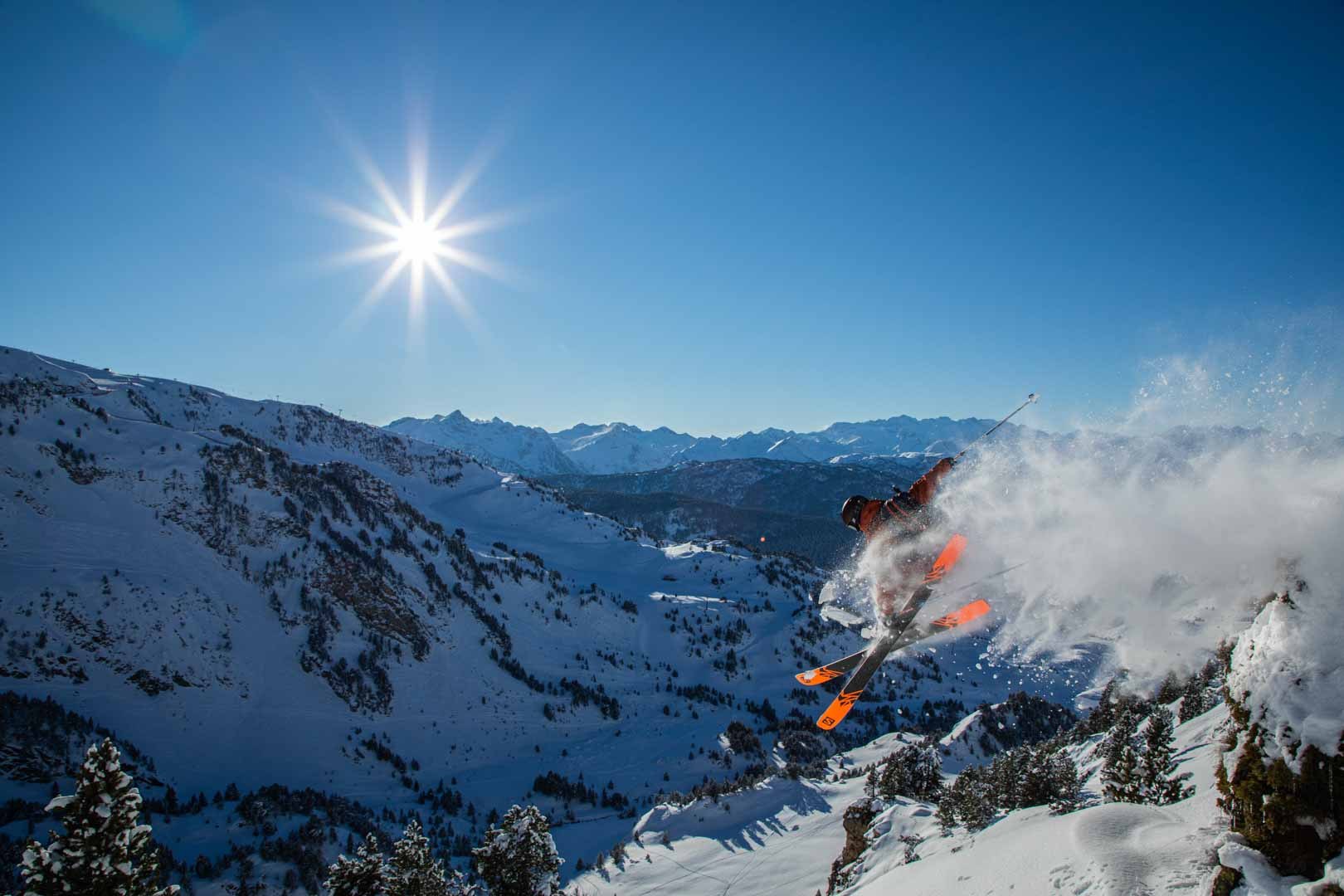 Freeride skier throwing a plume of snow across the mountains
