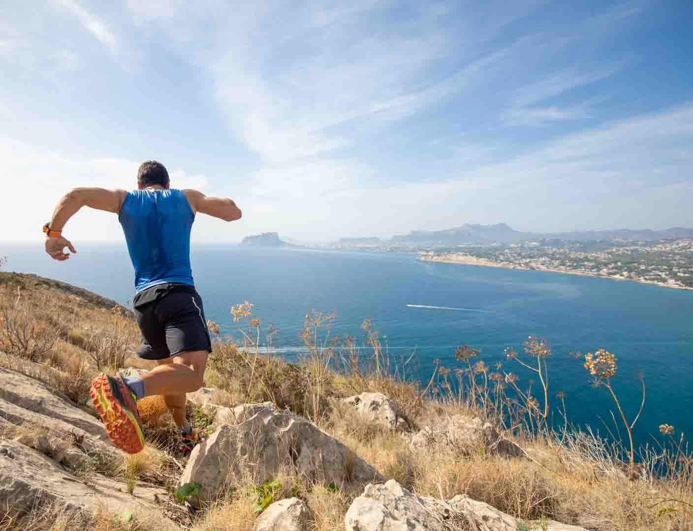Trail runner above a blue coastline