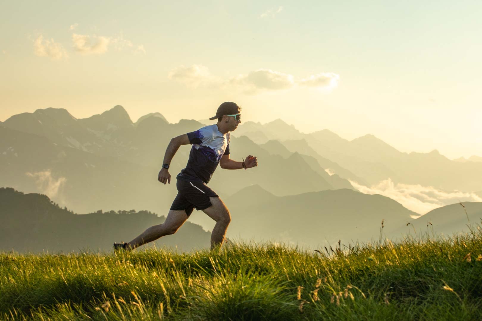 Trail runner crossing a sunlit mountain ridge