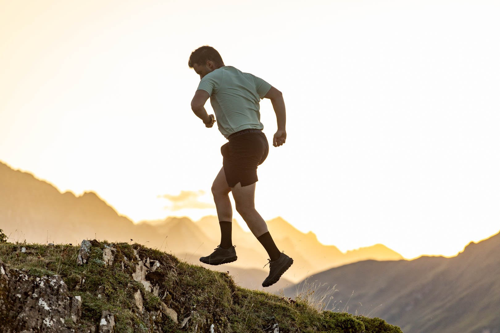 Trail runner silhouetted against the evening mountains